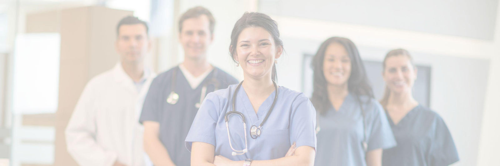 A group of family physicians standing together in scrubs smiling into the camera